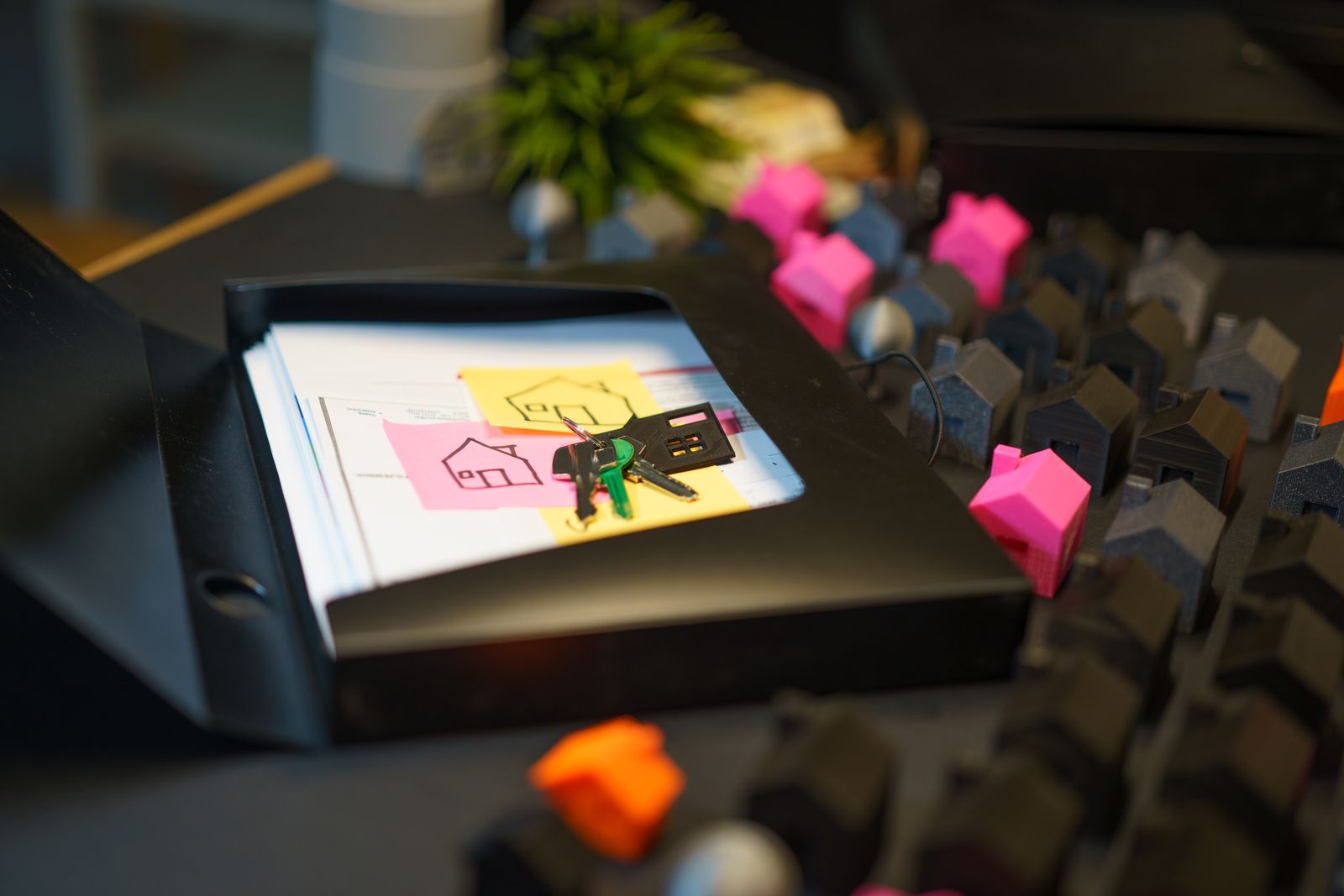 Clés posées sur un dossier de documents, entourées de petites maisons miniatures