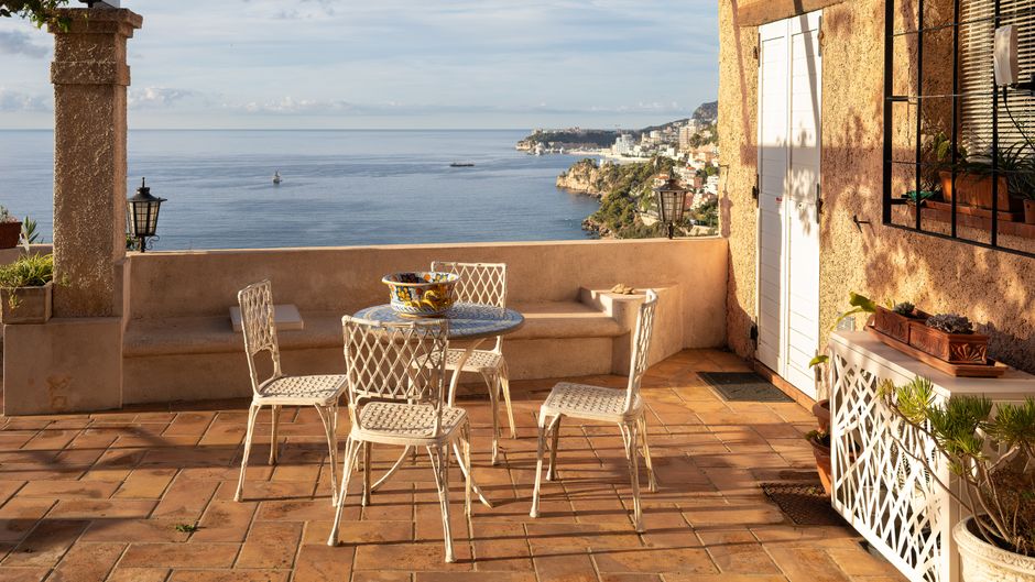 Terrasse en terre cuite avec table et chaises donnant sur la mer Méditerranée
