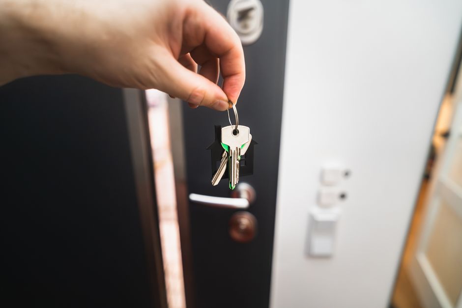 Main tenant un trousseau de clés devant une porte ouverte, image de location saisonnière (Jakub Zerdzicki / Pexels)