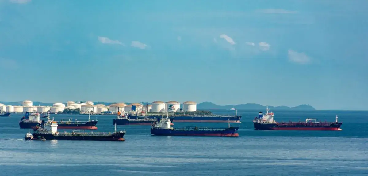 Cargos amarrés près de cuves de stockage de pétrole sur un littoral