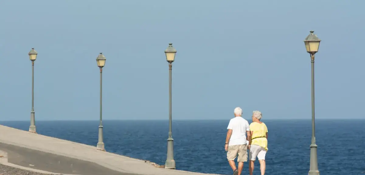 Un couple de retraités se promène sur une promenade en bord de mer