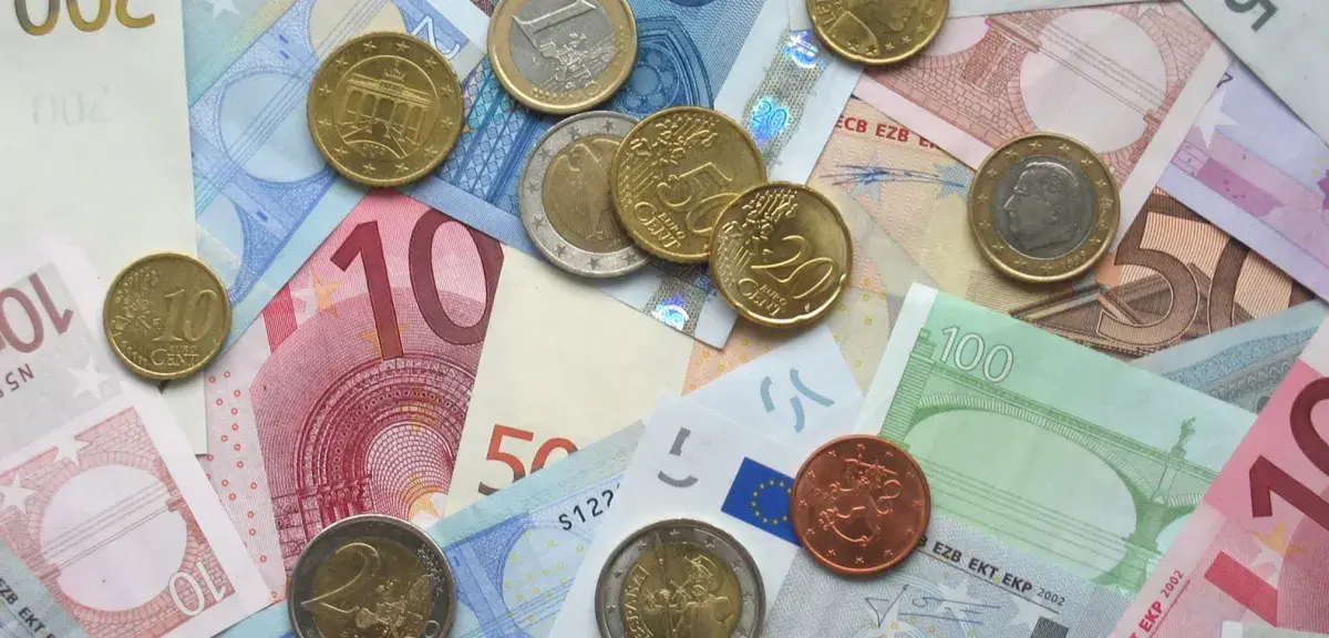Pièces et billets en euros étalés sur une table, symbole du salaire minimum