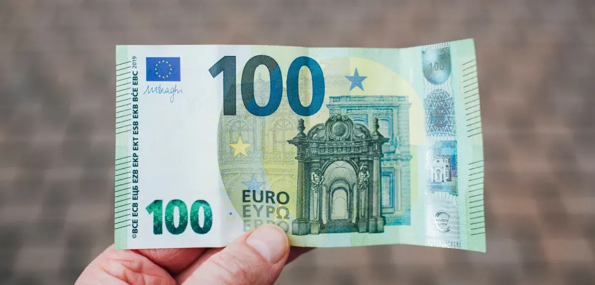 Une main tient un billet de 100 euros