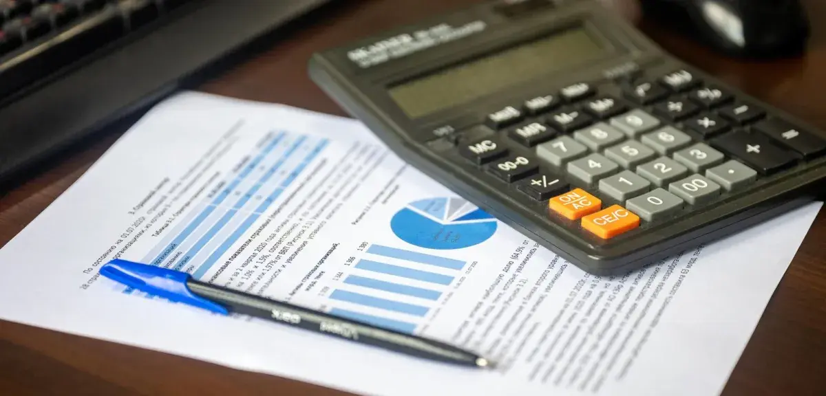 Calculatrice, stylo et document financier avec graphiques sur un bureau