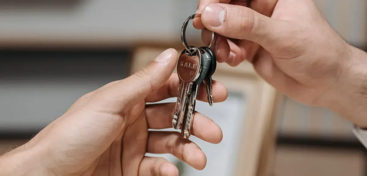 Deux mains échangent un trousseau de clés dans un intérieur