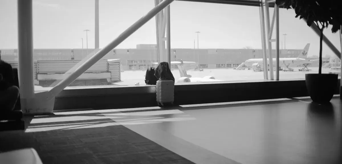 Valise devant une baie vitrée donnant sur le tarmac d'un aéroport