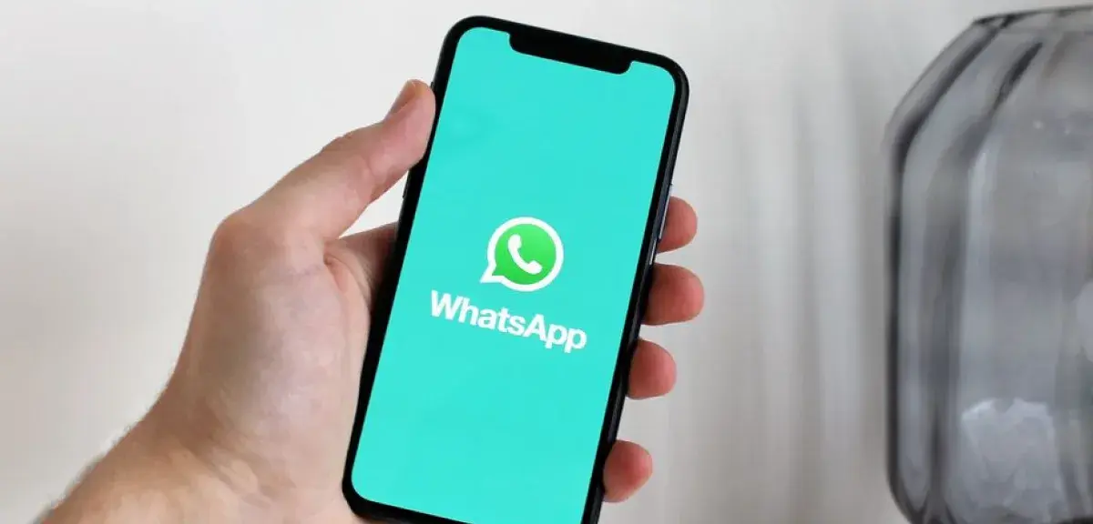 Main tenant un smartphone affichant l'application WhatsApp