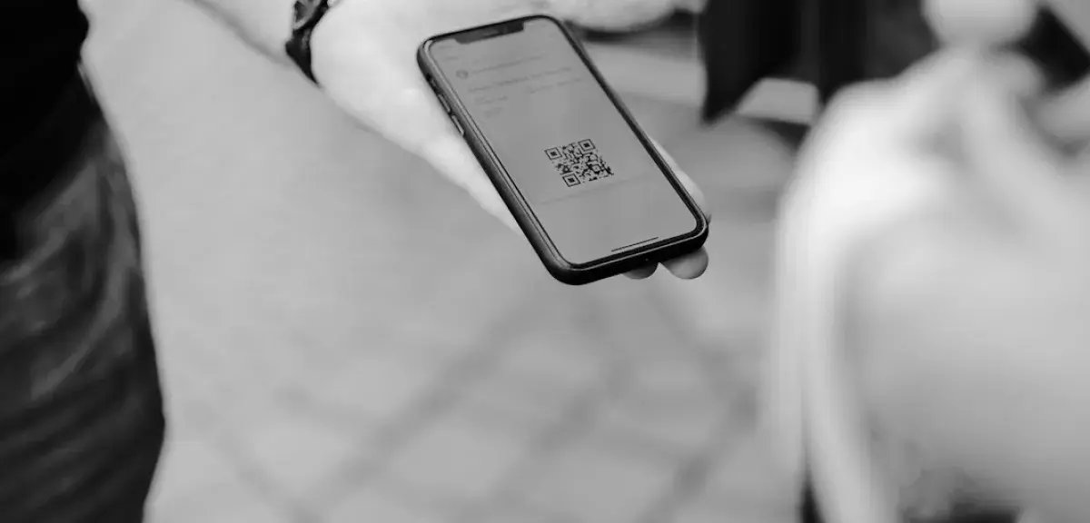 Une main tient un smartphone qui affiche un QR code
