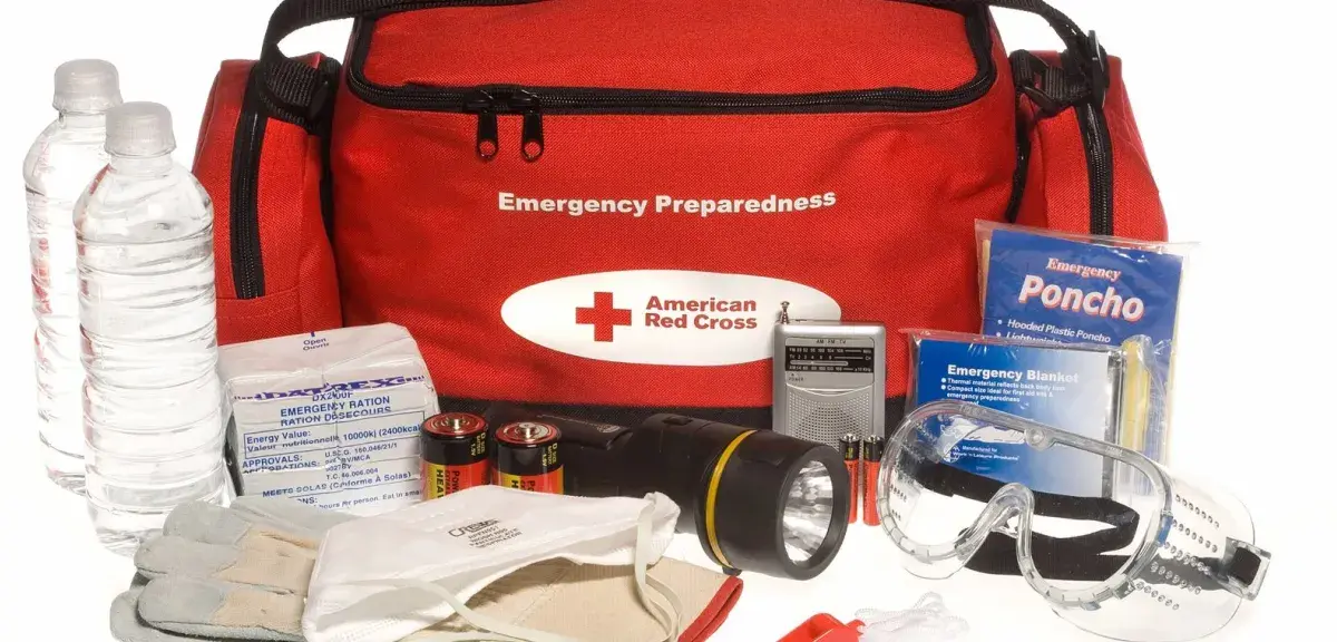 Sac d'urgence de la Croix-Rouge et son contenu : bouteilles d'eau, radio à piles, lampe torche, couverture de survie, gants et masque