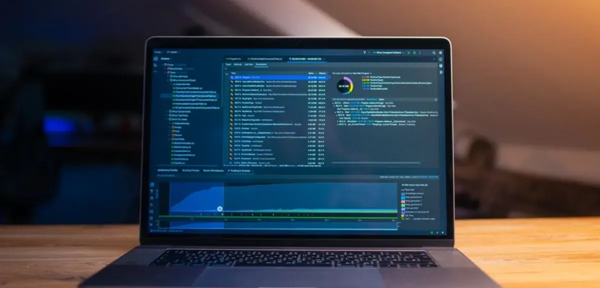 Ordinateur portable ouvert sur un bureau en bois, écran affichant un logiciel de développement