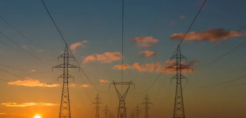 Lignes à haute tension traversant un paysage montagneux au coucher du soleil