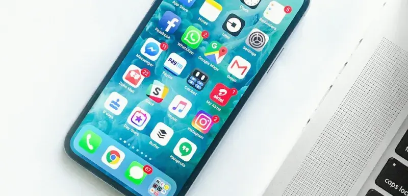 Smartphone posé sur un bureau à côté d'un ordinateur portable