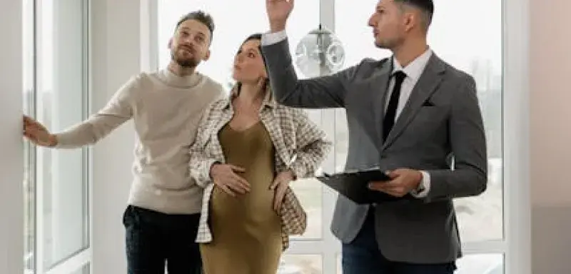 Un couple visite une maison moderne avec un agent immobilier, explorant leur potentiel nouveau logement