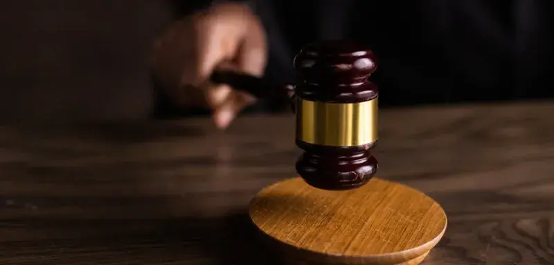 Un marteau de juge frappant un socle, symbolisant la justice et l'autorité légale dans un tribunal