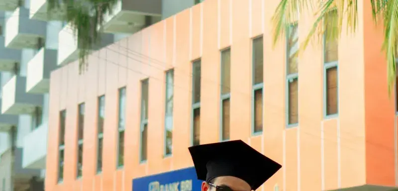 Un homme assis par terre en toge de diplômé