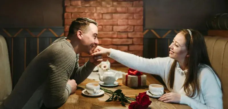 Couple face à face dans une ambiance tamisée de Saint-Valentin, entre romance et pression commerciale
