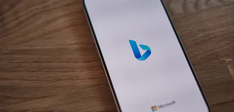 Un téléphone portable posé sur une table en bois affichant le moteur de recherche Bing