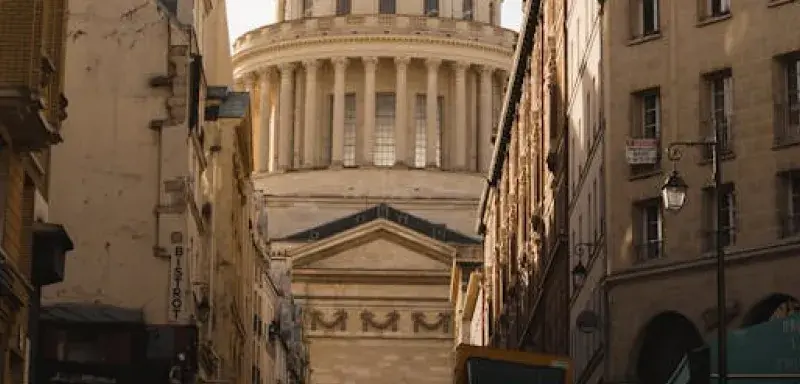 A breathtaking view of the Panthéon in Paris framed by historic buildings under a dramatic sky.