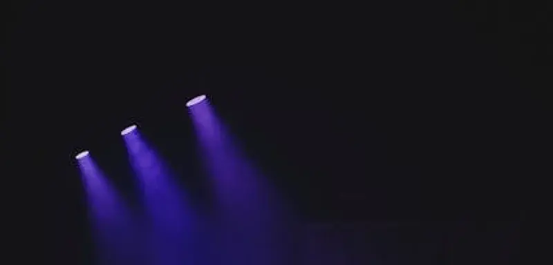 Moody theater scene with purple spotlights casting a vivid glow on an empty stage.