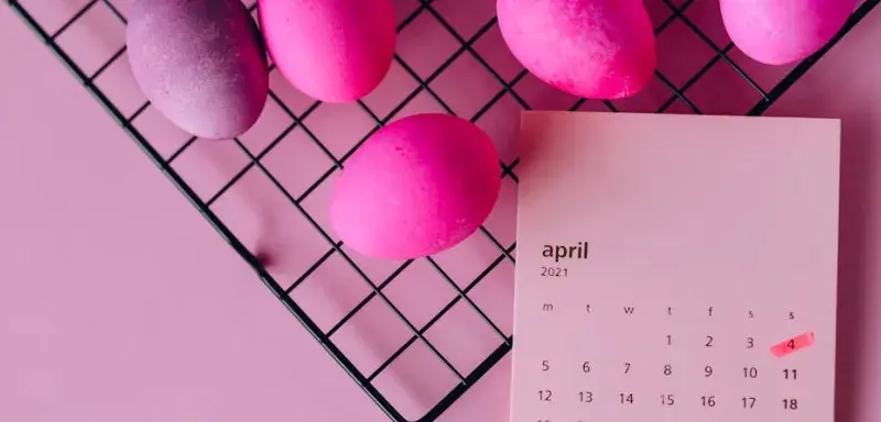 Œufs de Pâques colorés sur un support et calendrier d'avril 2021, symbolisant la célébration du printemps
