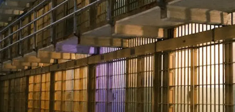 Intérieur sombre d'un bloc cellulaire de prison, montrant des rangées de barreaux d'acier