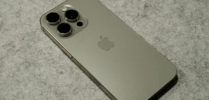 A silver iPhone sitting on top of a table in titanium finish
