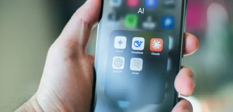 A hand holds a smartphone with various AI apps