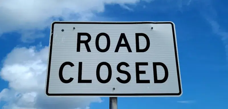 a road closed sign in front of a blue sky