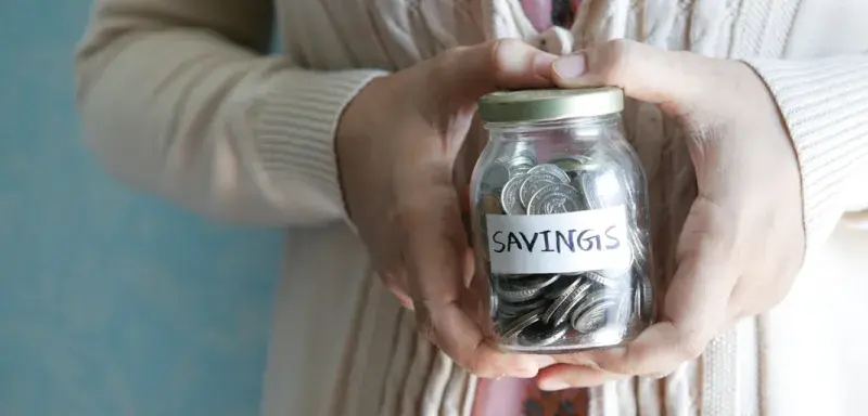a woman holding a jar with savings written on it