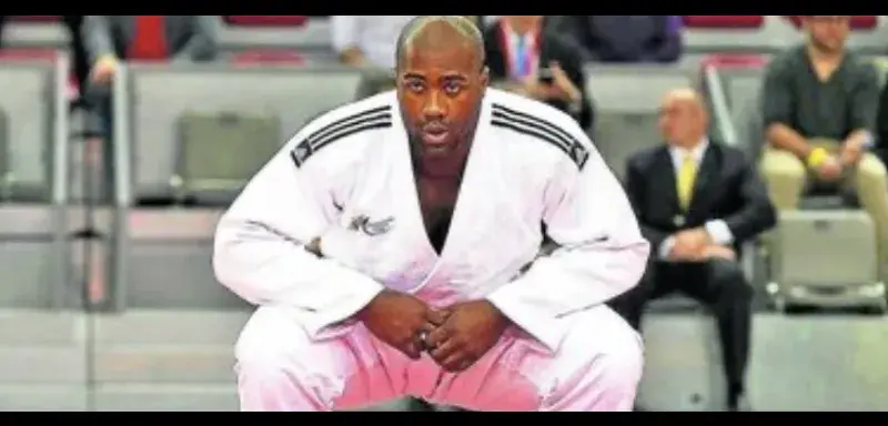 Two male adults engaged in judo practice on a dojo mat, showcasing martial arts technique.
