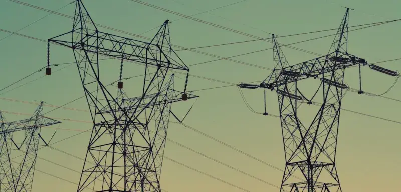 black transmission towers under green sky