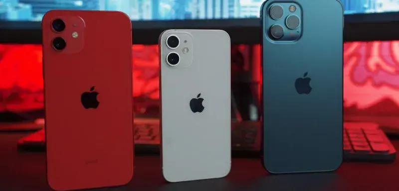Trois iPhone posés sur un bureau devant un écran