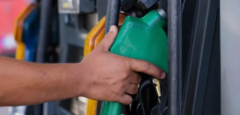 Main tenant un pistolet de pompe à carburant vert dans une station-service