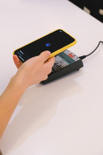 Personne payant avec un smartphone sur un terminal de paiement sans contact