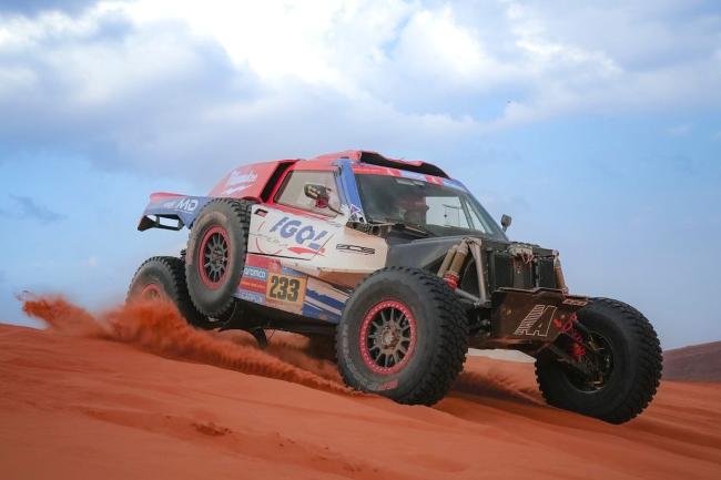 Un buggy de rallye-raid en pleine course dans les dunes rouges du désert, lors d'une édition précédente du Dakar