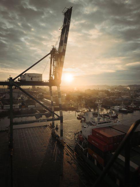 Grue et navires de charge dans un port au coucher du soleil