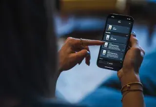 Femme utilisant un smartphone, illustrant les arnaques aux messages vocaux