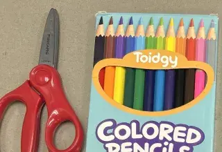 Ciseaux rouges et boîte de crayons de couleur, fournitures scolaires