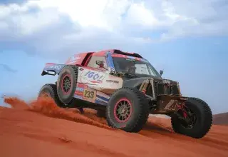 Un buggy de rallye-raid en pleine course dans les dunes rouges du désert, lors d'une édition précédente du Dakar