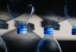Gros plan sur des bouteilles en plastique avec bouchons bleus projetant des ombres, illustrant les enjeux du recyclage