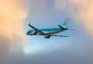 Un avion bleu et blanc volant dans un ciel nuageux