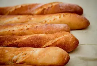 Baguettes de pain dorées alignées en boulangerie
