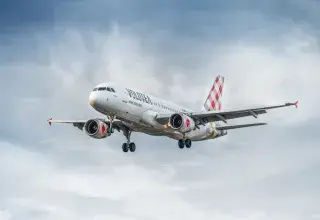 Un avion commercial Volotea en vol dans un ciel nuageux, photographié depuis le sol