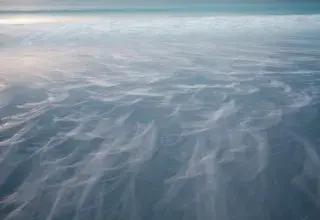 Paysage de montagne enneigé près d'un plan d'eau sous un ciel couvert