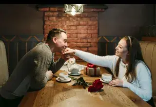 Couple face à face dans une ambiance tamisée de Saint-Valentin, entre romance et pression commerciale