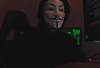 Silhouette mystérieuse portant un masque de Guy Fawkes, éclairée par des écrans d'ordinateur dans une pièce sombre