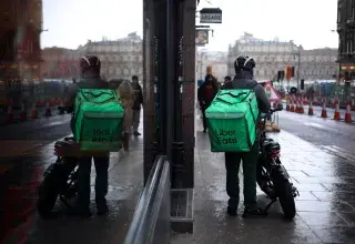 Livreur Uber Eats à moto dans une rue pluvieuse d'Édimbourg avec reflet dans le rétroviseur