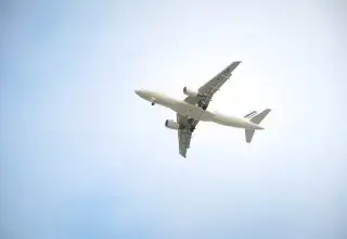 Un avion commercial blanc volant haut dans un ciel bleu dégagé