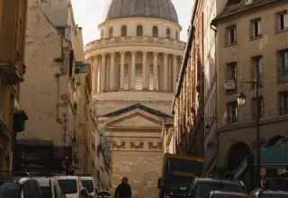 A breathtaking view of the Panthéon in Paris framed by historic buildings under a dramatic sky.