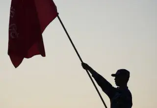 Silhouette d'un soldat brandissant un drapeau au coucher du soleil, évoquant patriotisme et unité